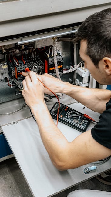 Žmogus spaudžia RCD test mygtuką elektros skydelyje, tikrinant nuotėkio apsaugą