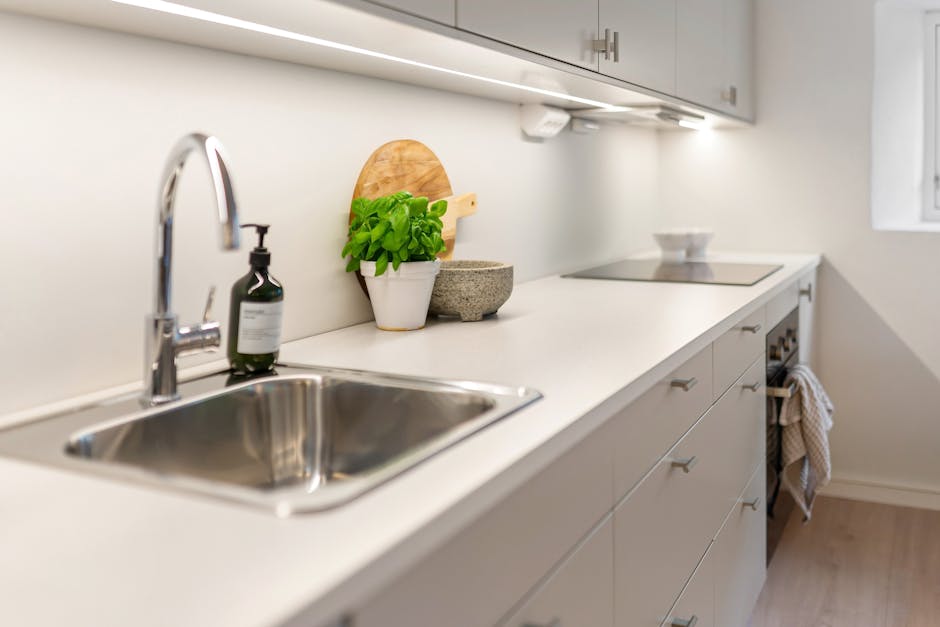 Šviesa nuo LED juostos apšviečia virtuvės stalviršį prie kriauklės