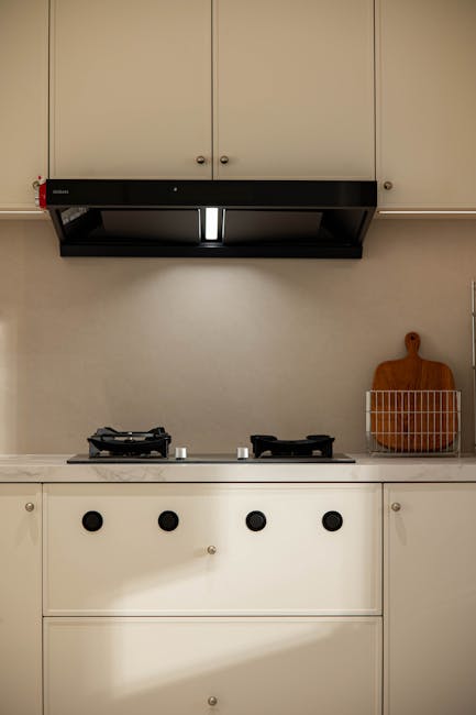 Virtuvėje veikiantis gartraukis virš viryklės, matosi oro srauto poveikis patalpoje