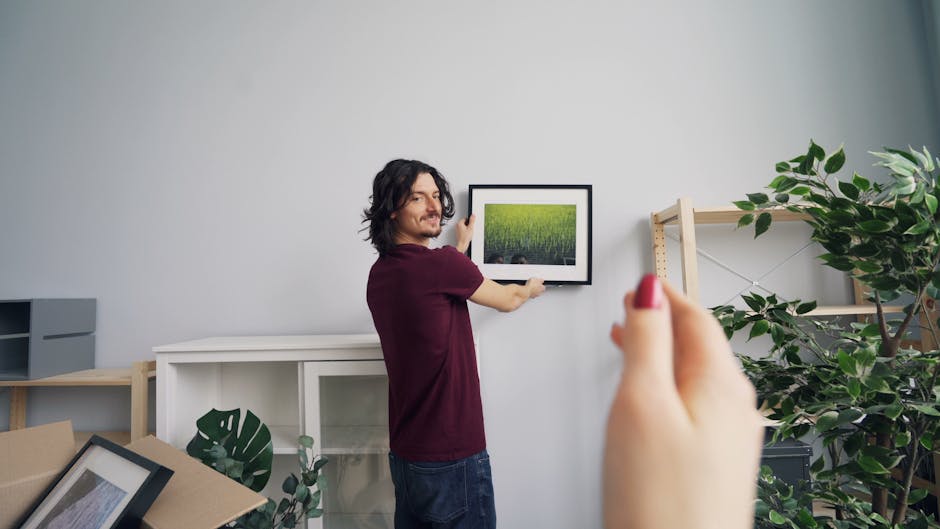 Žmogus montuoja lentyną su gulsčiuku ir matavimo įrankiais namuose